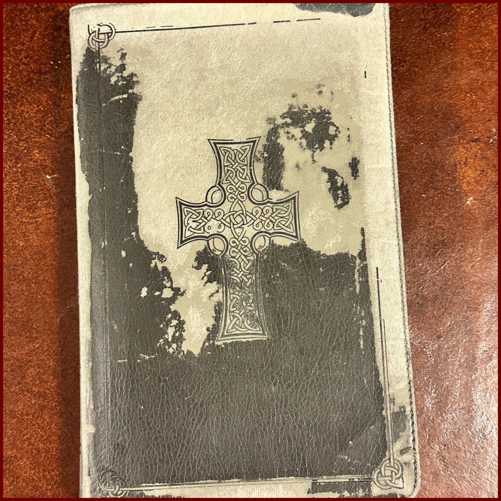 The worn leather cover of the Bible Adam Pritchett gave Todd, stamped with a Celtic cross